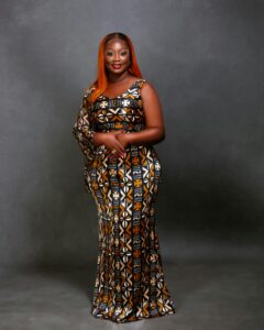 Portrait of a woman in a vibrant traditional dress against a gray background.
